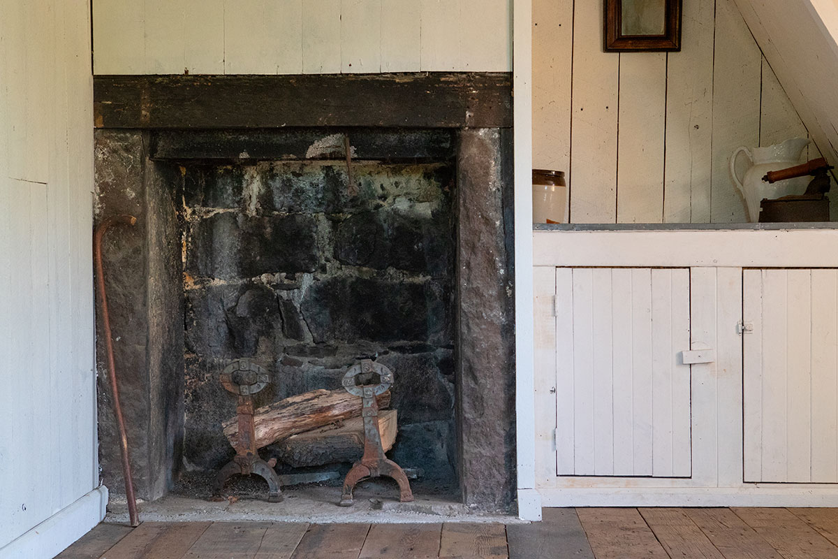 Intérieur de la maison natale de l'artiste, montrant la foyer et, à sa droite, un comptoir avec cruche, pot et fer à repasser.