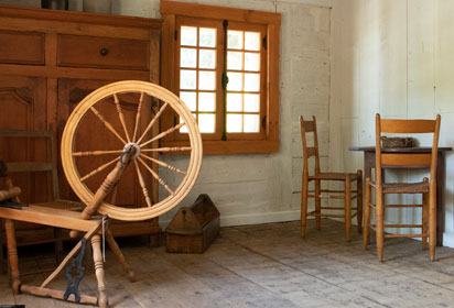 Vue de l'intérieur de la maison natale avec rouet, table et mobilier.
