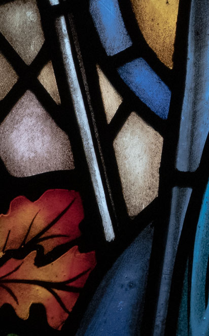 Détail d'un vitrail d'église représentant Marie priant. On aperçoit une feuille de chêne du côté gauche.