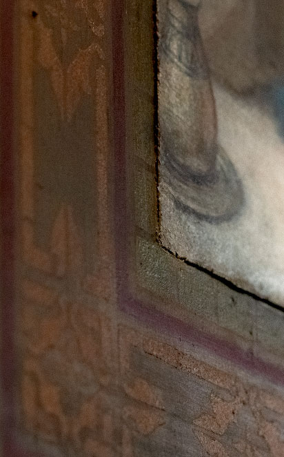 Détail de la technique de marouflage où on voit en gros plan le coin d'un canevas peint, fixé sur un mur ornementé d'une église.