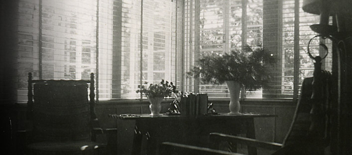 Détail de l'intérieur de la maison de Borduas, avec deux chaises et une table près d'une fenêtre.